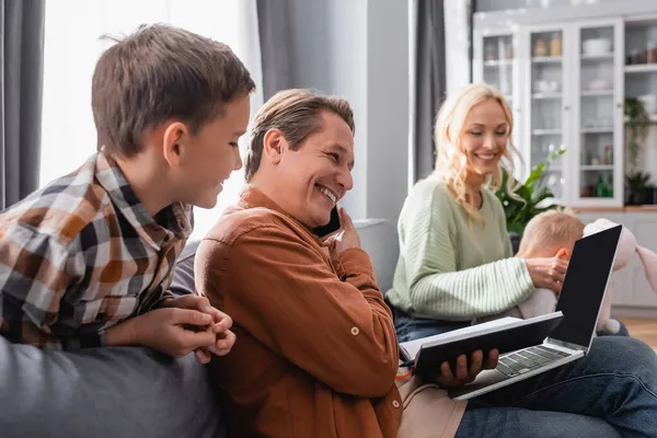 Glimlachende Man Praten Smartphone Tijdens Het Werken Buurt Van Vrouw — Stockfoto