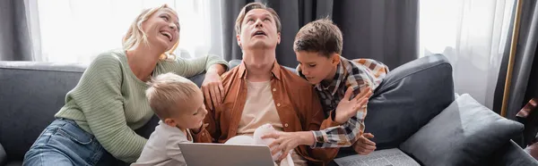 Drukke Uitgeputte Man Met Laptop Buurt Vrolijke Familie Plezier Hebben — Stockfoto