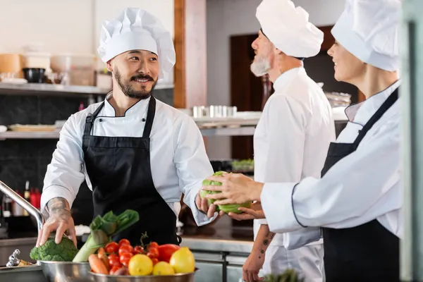 Smiling Asian Chef Giving Vegetable Colleague Restaurant Kitchen — Stock Photo, Image