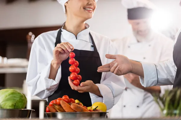 Šéf Ukazuje Cherry Rajčata Poblíž Usmívající Kolegyně Kuchyni Restaurace — Stock fotografie