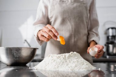 Aşçının mutfak masasına yumurta sarısı dökerkenki görüntüsü. 
