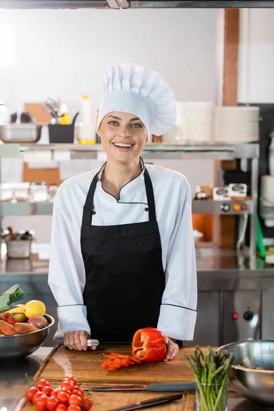 Glimlachende Chef Met Mes Paprika Terwijl Hij Naar Camera Keuken — Stockfoto