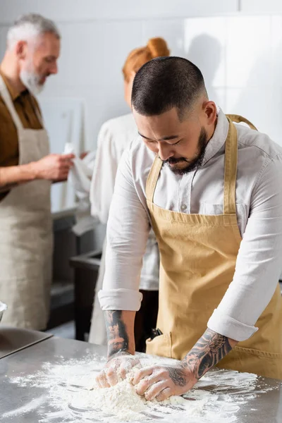 Chef Asiático Haciendo Masa Cerca Colegas Borrosos Cocina — Foto de Stock