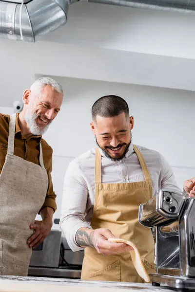 Cheerful Asian Chef Holding Dough Pasta Maker Machine Colleague Kitchen — Stock Photo, Image