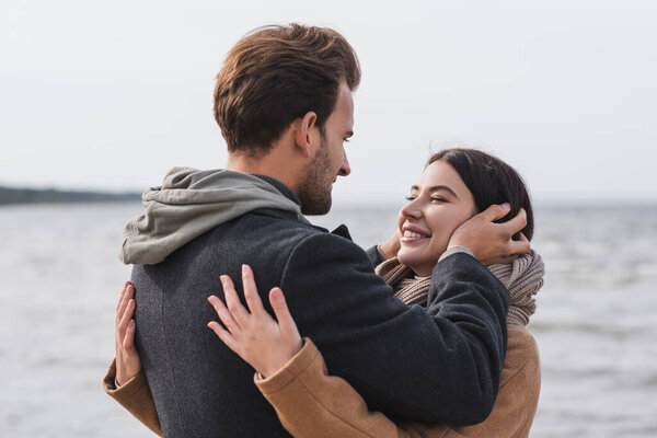 happy young couple embracing near sea during autumn walk