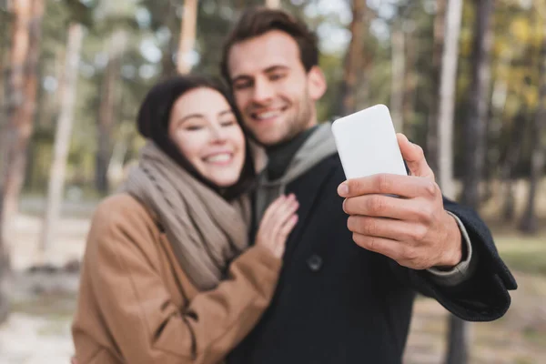 Casal Desfocado Feliz Tomando Selfie Smartphone Enquanto Caminhava Floresta Outono — Fotografia de Stock