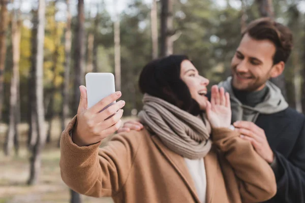 Heyecanlı Kadın Cep Telefonuyla Selfie Çekiyor Erkek Arkadaşıyla Ormanda Bulanık — Stok fotoğraf