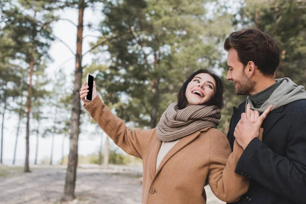 Sonbahar Ceketli Neşeli Kadın Parkta Yürürken Cep Telefonuyla Selfie Çekiyor — Stok fotoğraf
