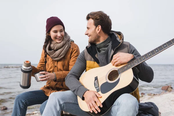 Femme Gaie Avec Thermos Homme Avec Guitare Assis Bord Rivière — Photo