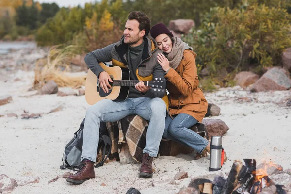 Junger Mann Spielt Bei Spaziergang Neben Glücklicher Frau Lagerfeuer Gitarre — Stockfoto