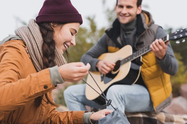 Uomo Sfocato Suonare Chitarra Vicino Sorridente Donna Chiusura Zaino — Foto Stock