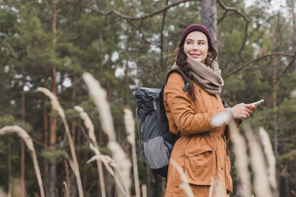 Usmívající Žena Mobilním Telefonem Batohem Dívá Pryč Při Turistice Rozmazané — Stock fotografie