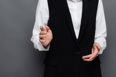 Kırpılmış iş kadını görüntüsü gri arka planda kamerayı işaret ediyor.