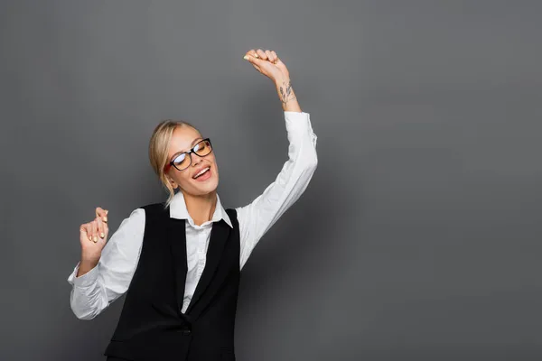 Excited businesswoman in shirt and eyeglasses closed eyes isolated on grey