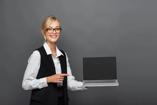 Gözlüklü Gülümseyen Kadını Gri Ekranda Boş Ekranla Dizüstü Bilgisayarı Işaret — Stok fotoğraf