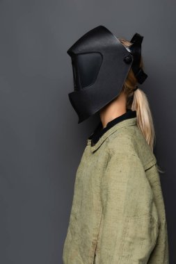 Maskeli ve üniformalı sarışın kaynakçı gri yolda izole edilmiş. 