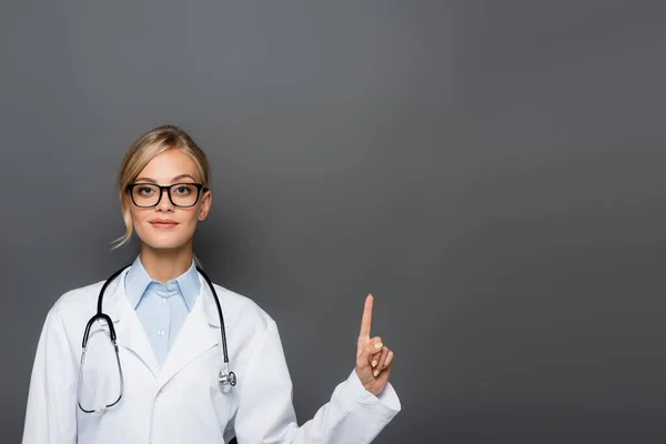 Junger Arzt Weißen Kittel Zeigt Mit Finger Auf Grau — Stockfoto