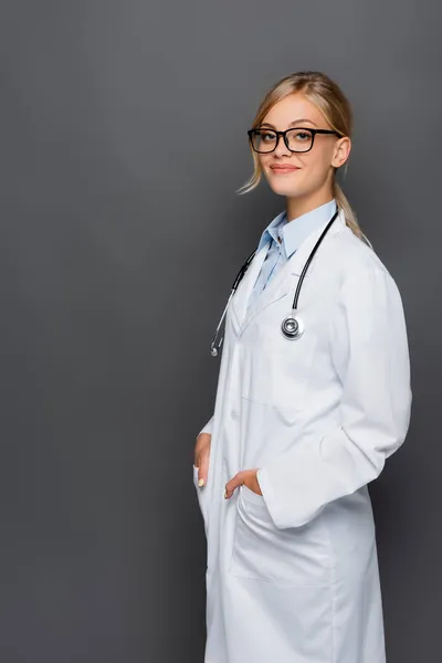 Cheerful Doctor White Coat Holding Hands Pockets Looking Camera Isolated — Stock Photo, Image