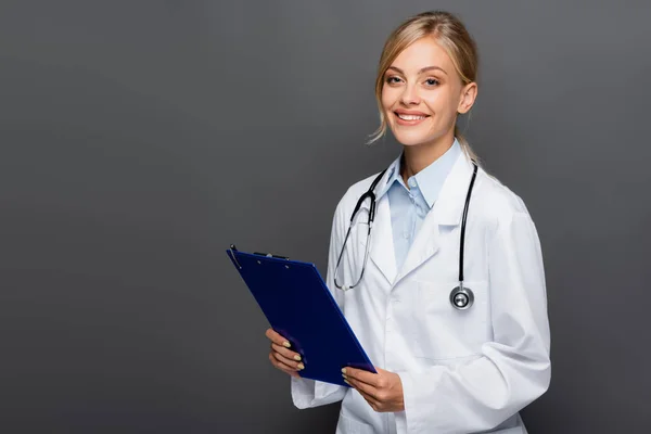 Happy Young Doctor Holding Clipboard Looking Camera Isolated Grey — Stock Photo, Image