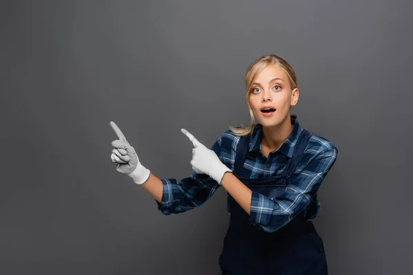 Verblüffte Arbeiterin Handschuhen Zeigt Mit Fingern Auf Grau Isoliert — Stockfoto