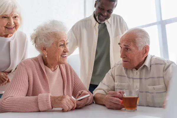 Positive Multiethnic Senior Friends Smartphone Tea Talking Nursing Home — Stock Photo, Image