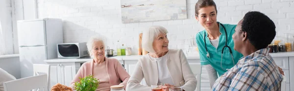 Vidám Idős Fajok Közötti Nők Beszélgetnek Ápolónővel Idősek Otthonában Transzparens — Stock Fotó