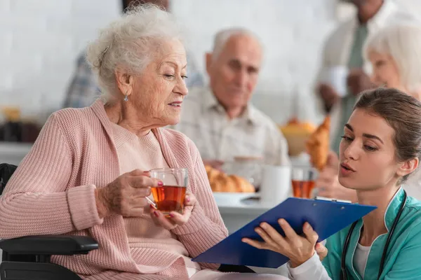 Sjuksköterska Håller Urklipp Nära Äldre Patient Med Rullstol Vårdhemmet — Stockfoto