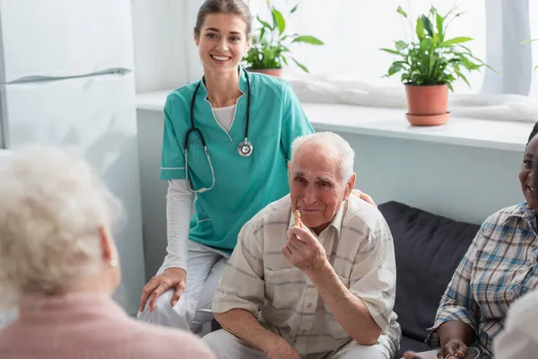 Smiling Nurse Sitting Senior Interracial Patients Chess Figure Nursing Home — Stock Photo, Image