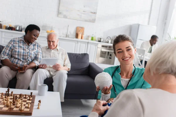 Enfermera Sonriente Sosteniendo Hilo Cerca Del Paciente Hogar Ancianos — Foto de Stock