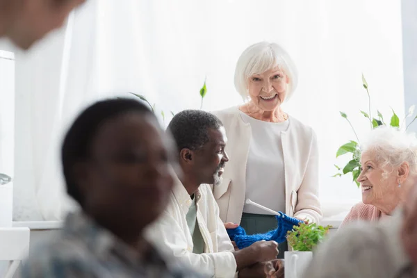 Äldre Kvinna Som Håller Garn Nära Multietniska Pensionärer Vårdhem — Stockfoto