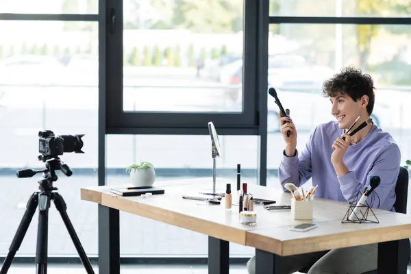 Cheerful Transgender Makeup Artist Holding Cosmetic Brushes Cosmetics Digital Camera — Stock Photo, Image