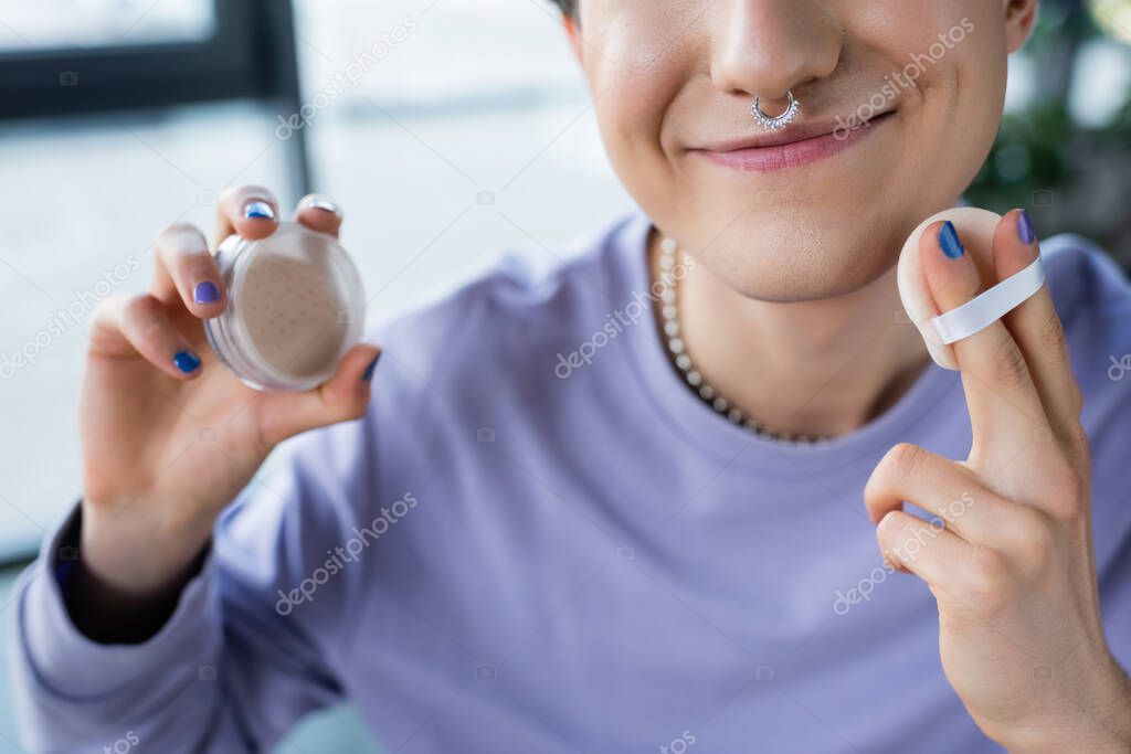 Cropped view of smiling transgender person holding face powder 