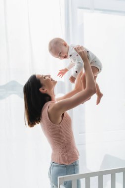 Gülümseyen esmer kadın heyecanlı küçük oğlunu kaldırdı.