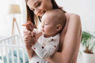 Küçük oğlan gülen annenin ellerine dokunuyor.