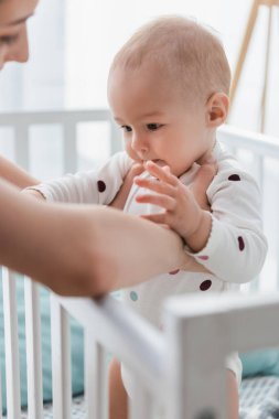 Bulanık kadın, beşikte duran bebeğe destek oluyor.