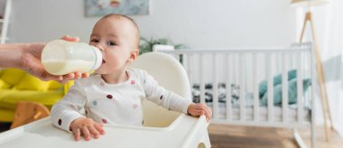 Bebek sandalyesinde otururken süt içen çocuk, afiş.