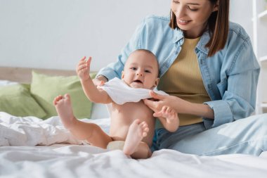 Mutlu esmer kadın, küçük oğlunu yatak odasına tıkıyor.
