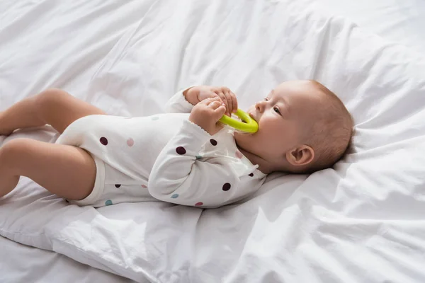 Toddler Boy Biting Toy While Lying White Bedding Romper — Stock Photo, Image