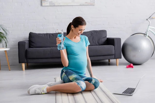 Glücklich Schwangere Frau Schaut Auf Laptop Während Sie Sportflasche Hält — Stockfoto