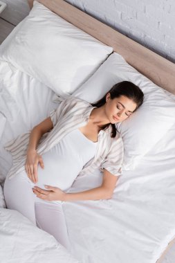 Genç hamile bir kadının yatakta uyuduğu en iyi manzara.