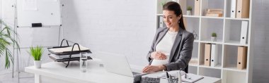 happy pregnant businesswoman looking at laptop in office, banner clipart