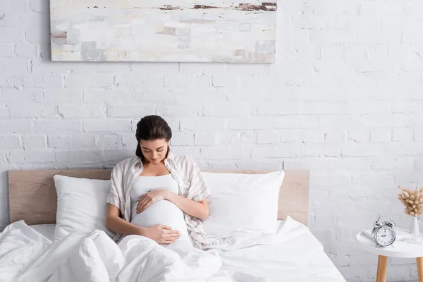 快乐而又怀孕的年轻女子在卧室里摸着肚子 — 图库照片