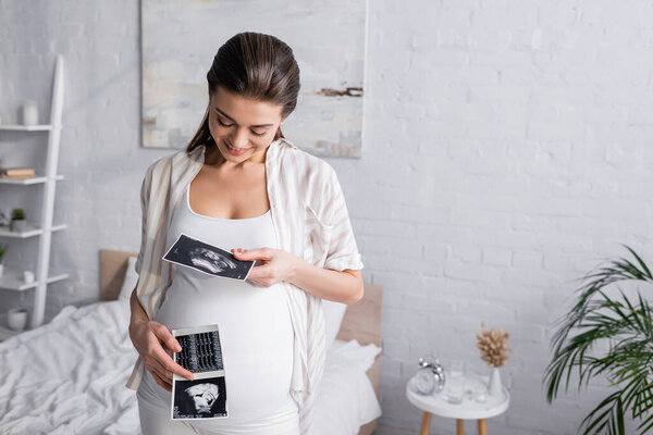 pleased pregnant woman holding ultrasound scans 