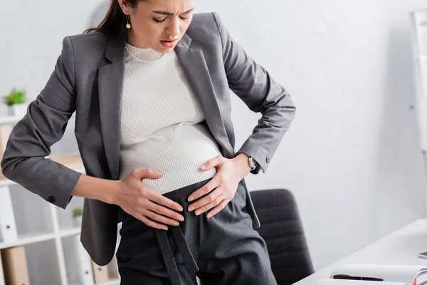 Jovem Mulher Negócios Grávida Tocando Barriga Enquanto Sente Cãibra — Fotografia de Stock