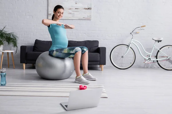 在现代客厅的健身球上锻炼的孕妇微笑着 — 图库照片
