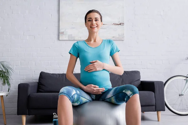 Fröhliche Schwangere Sportlerin Sitzt Auf Fitnessball Und Blickt Die Kamera — Stockfoto