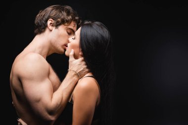 side view of young and sexy couple with closed eyes kissing on black  clipart