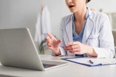 Hastanedeki pano ve dizüstü bilgisayarın yanında doktorla görüntüsü kesilmiş. 