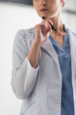 Laboratuvarda cam panoda formüllerin yanında duran kimyagerin kısmi görüntüsü