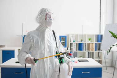 Laboratuvarı dezenfekte ederken koruyucu giysili doktor elinde sprey tutuyordu.